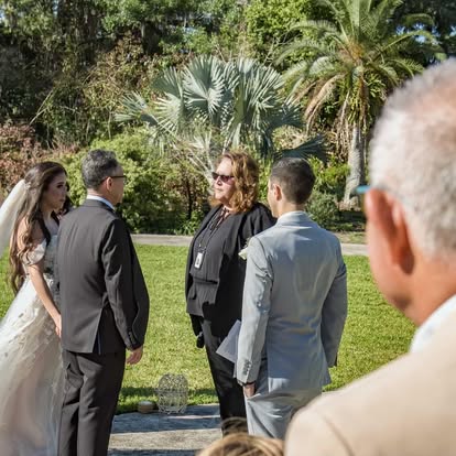 Wedding ceremony beside palms and a garden lawn