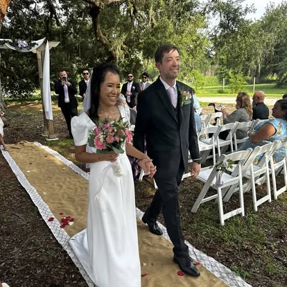 Newlyweds walking down an outdoor aisle