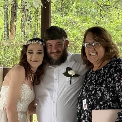 Esther with newlyweds beneath a wooden shelter