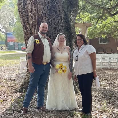 Esther with a wedding couple beneath a large tree