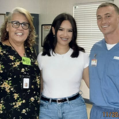 Esther smiling with a couple indoors