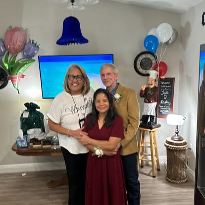Esther with a couple at an indoor celebration