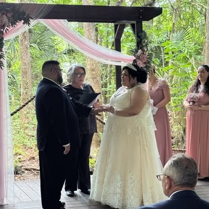 Esther officiating beneath a pink-and-white draped arbor