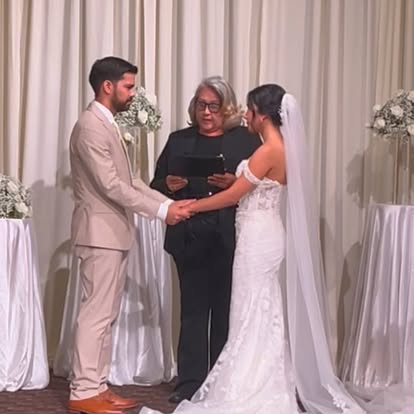 A couple holding hands while Esther leads their indoor wedding ceremony