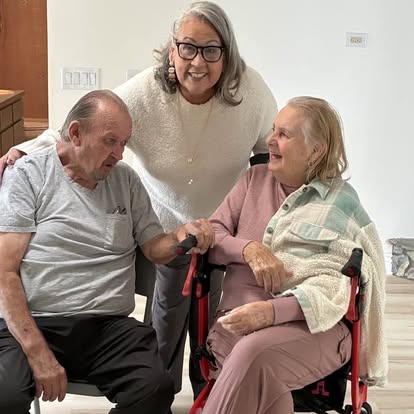 Esther smiling with a couple during an indoor celebration
