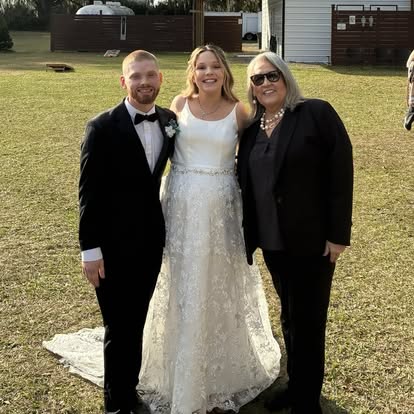 Esther with newlyweds on a green lawn