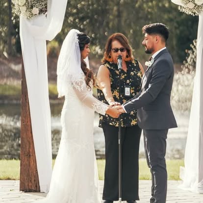 Esther officiating a wedding beneath a white outdoor arbor
